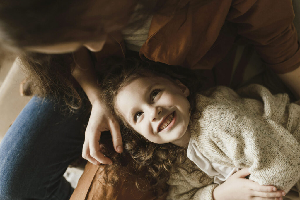 A happy child smiling while lying in lap of adult